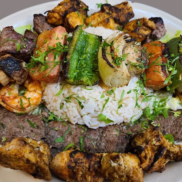A large platter of Wael's Mediterranean Cuisine's grilled meats, vegetables, shrimp, and rice.