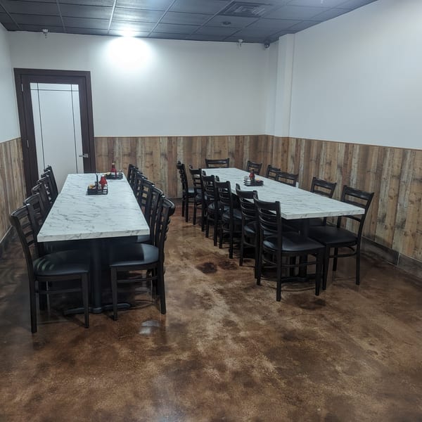 Empty dining room at Wael's Mediterranean Cuisine with long marble tables and black chairs.