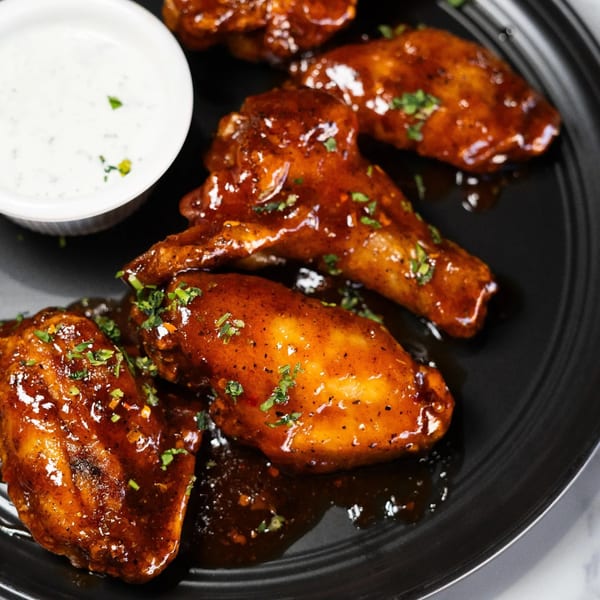 Wael's Mediterranean Cuisine's chicken wings, glazed in a rich sauce and garnished with herbs, served with a side of ranch.